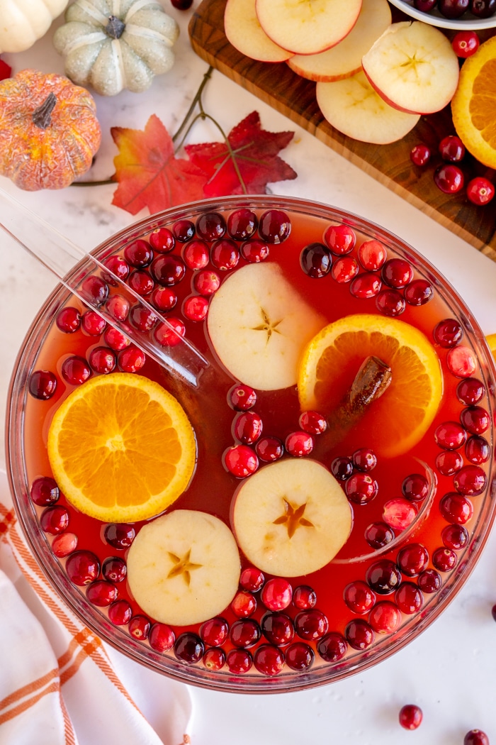 Thanksgiving Punch in large clear punch bowl with apple slices and orange slices