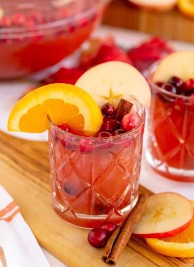 Thanksgiving Punch Recipe in individual clear glass garnished with apple slices, orange slice, and fresh cranberries