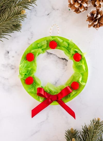 Let the kids get in the holiday spirit with this super easy Paper Plate Wreath! Grab a few basic materials and deck the halls with this festive craft!