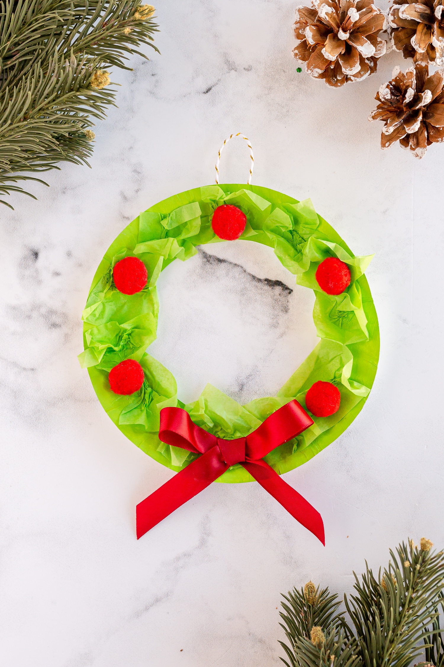 Let the kids get in the holiday spirit with this super easy Paper Plate Wreath! Grab a few basic materials and deck the halls with this festive craft!