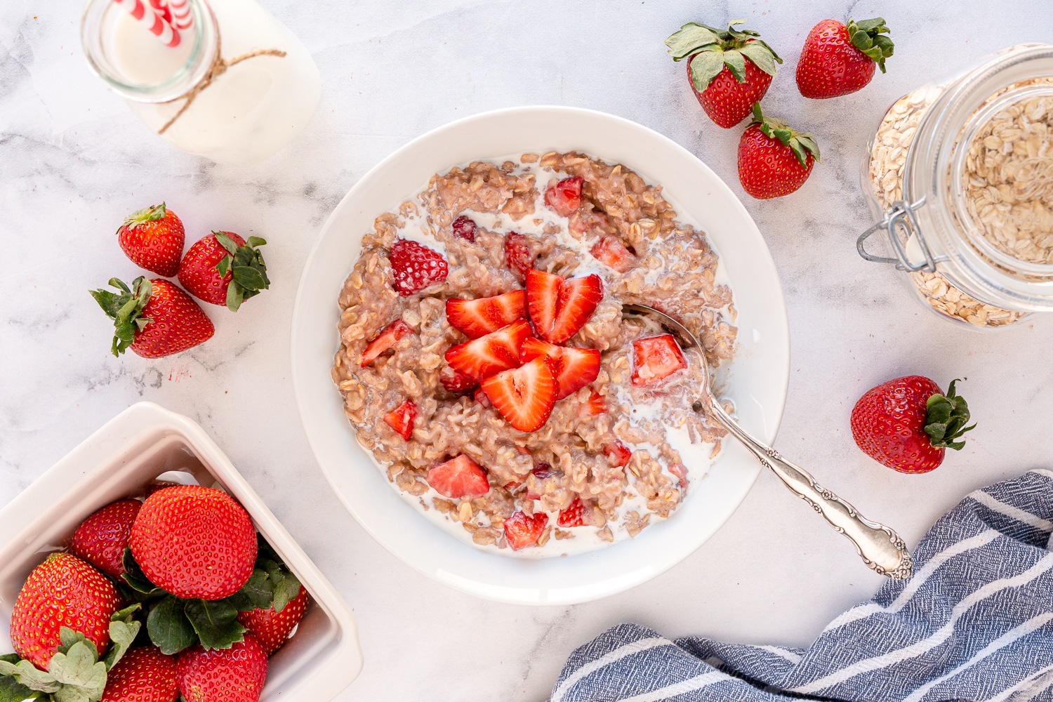 strawberries and cream oatmeal in a bowl with additional cream