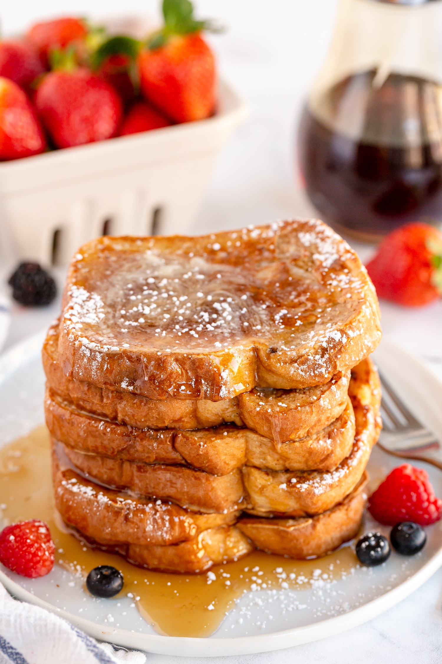stack of french toast on white plate with fresh berries