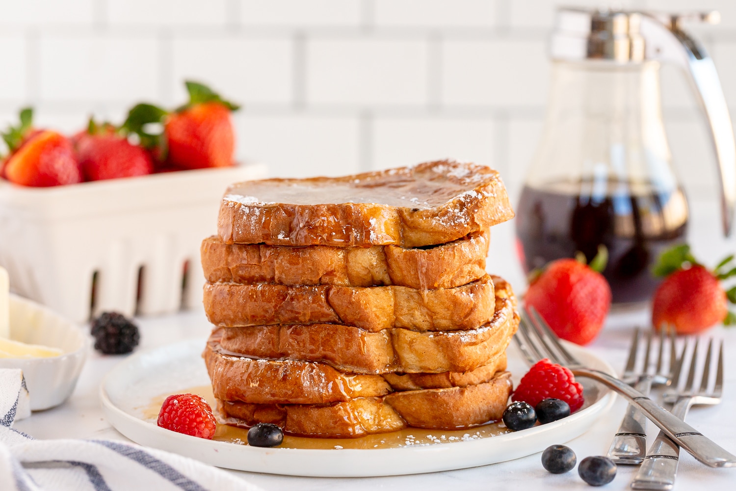 stack of french toast on white plate and syrup