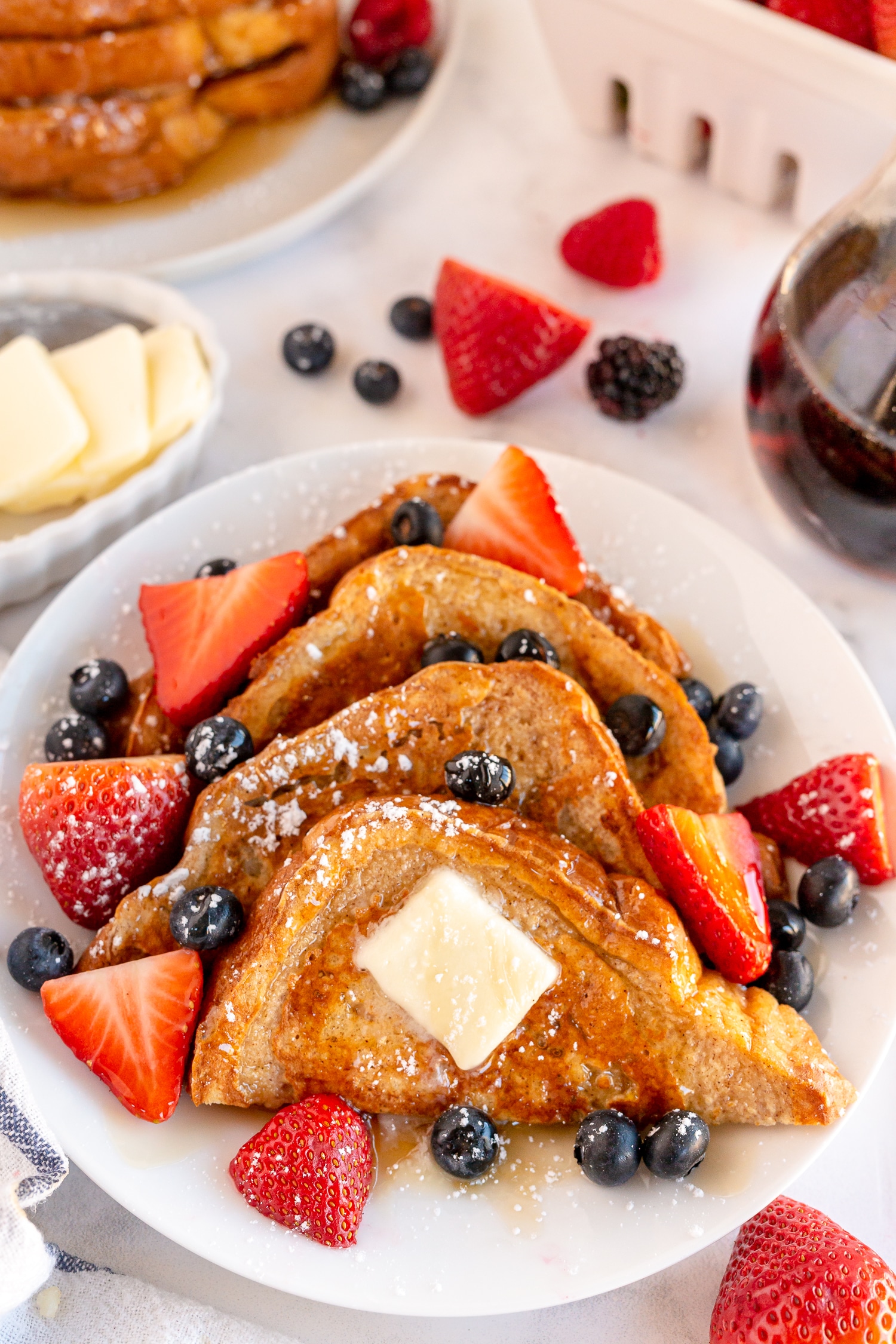 classic french toast on white plate served with berries and syrup