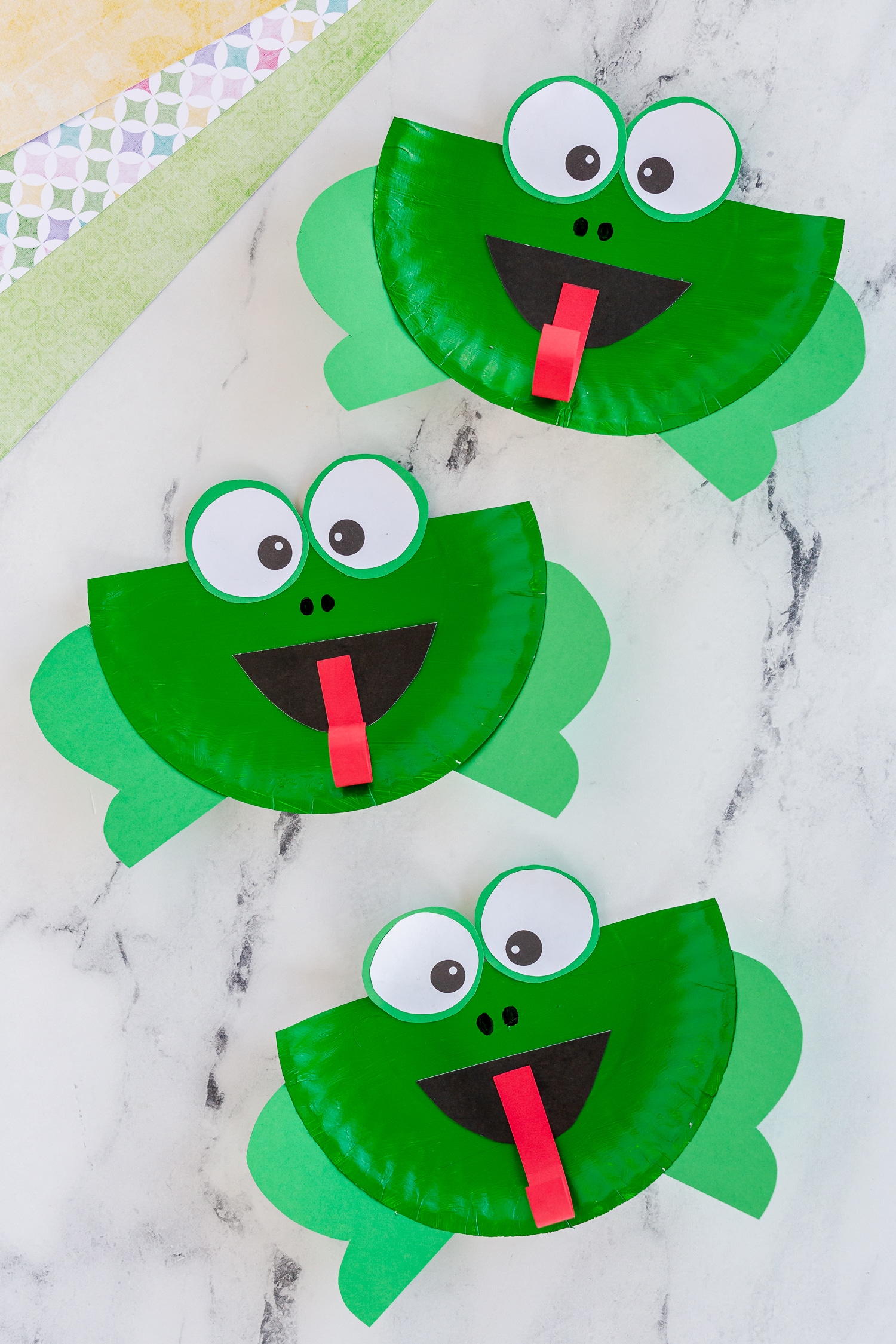 three completed paper plate frogs on counter
