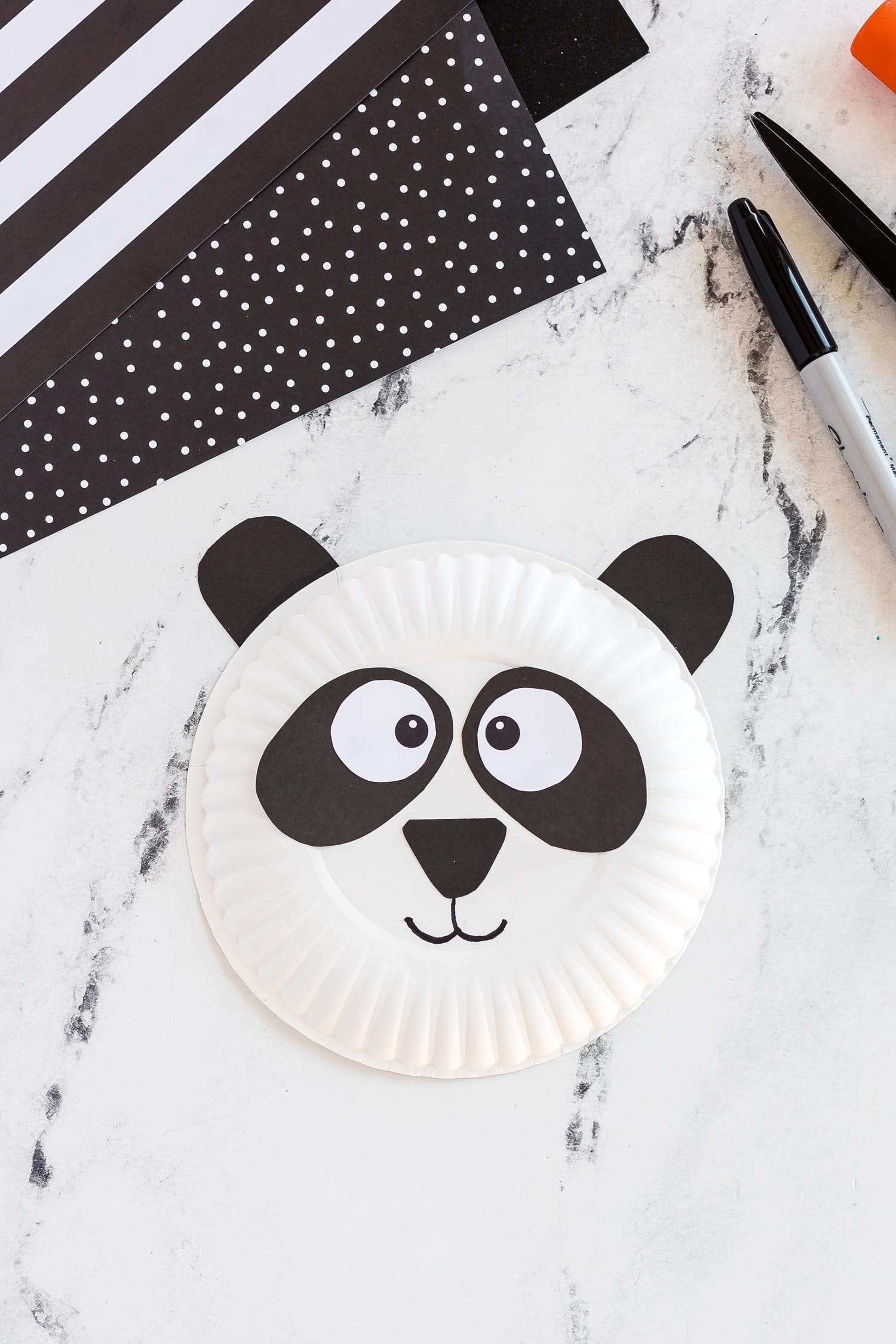 Paper plate panda on counter with black and white paper