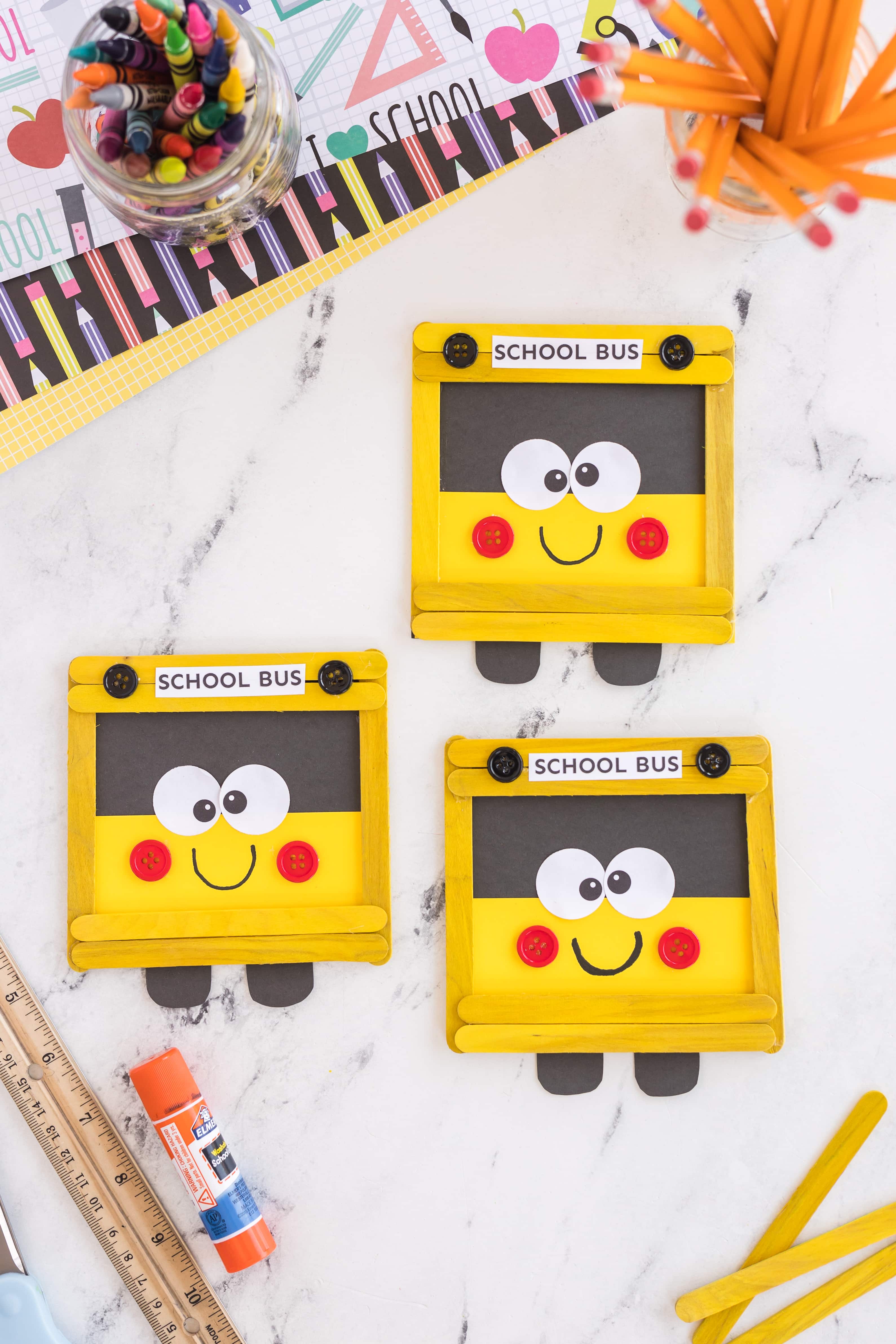 Three school bus craft on counter with school supplies