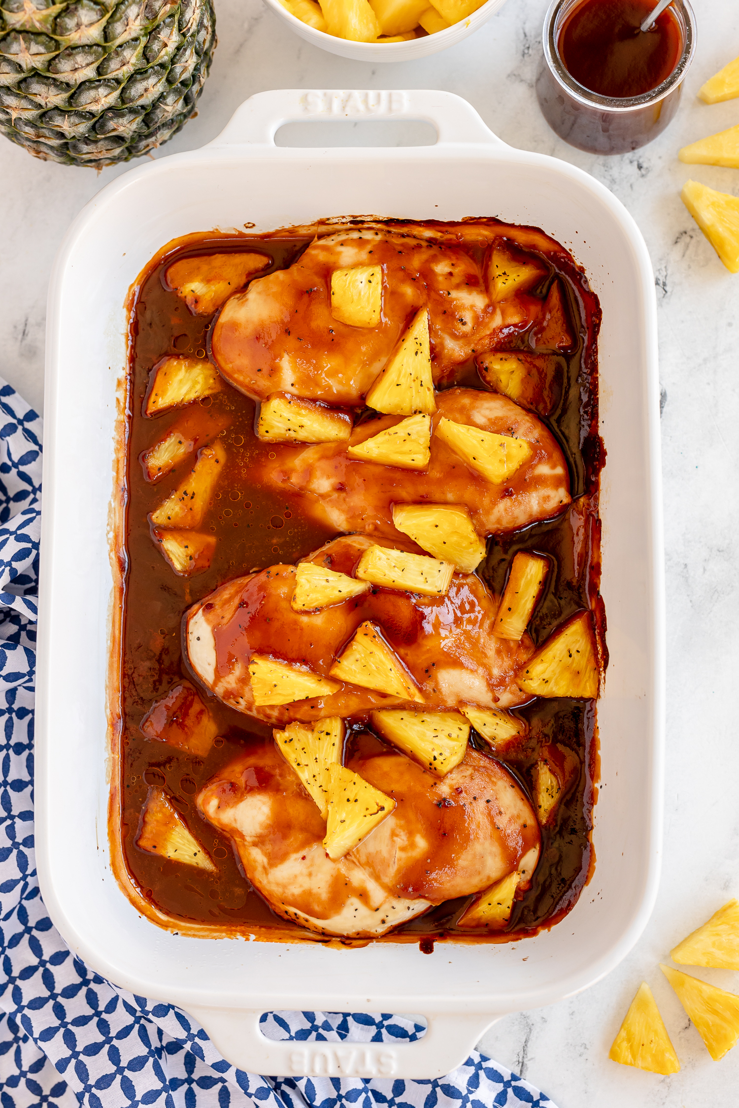 4 cooked chicken breasts in baking dish with cooked pineapple on top