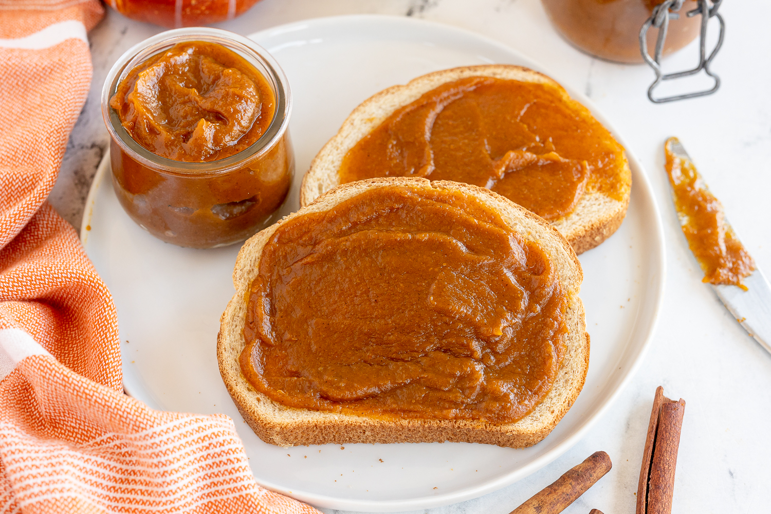 Pumpkin Butter spread on two pieces of toast on a white plate with an orange linen napkin