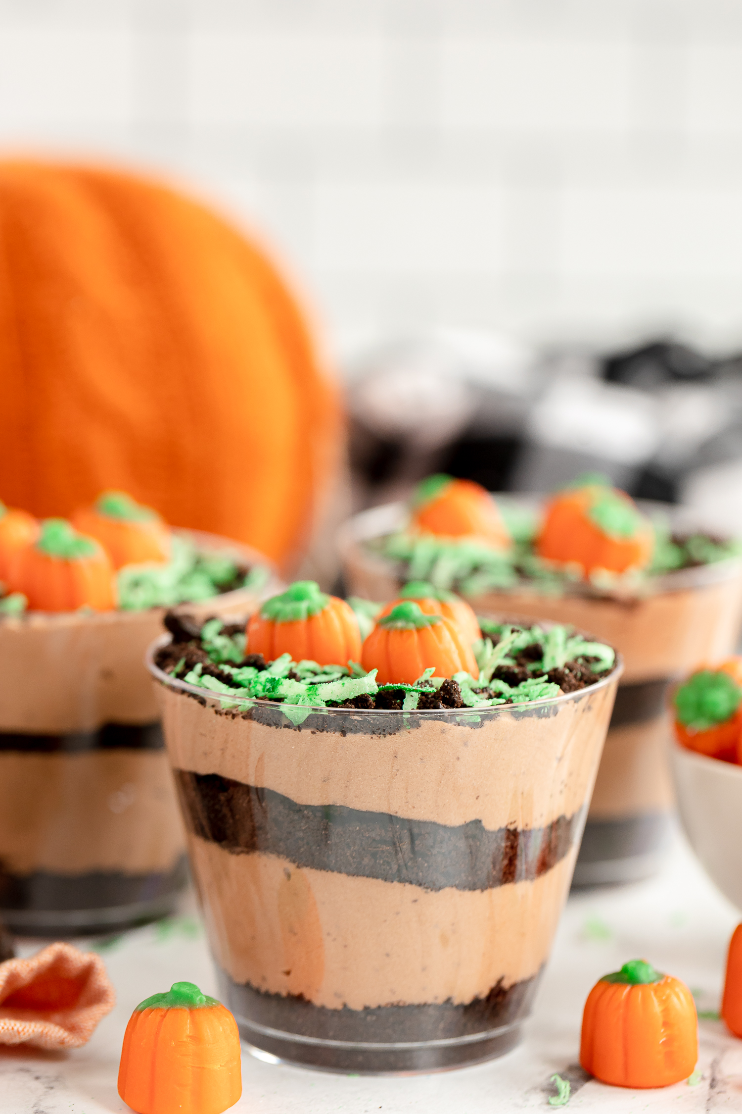 Pumpkin dirt cups on counter with chocolate pudding and cookie crumb layers