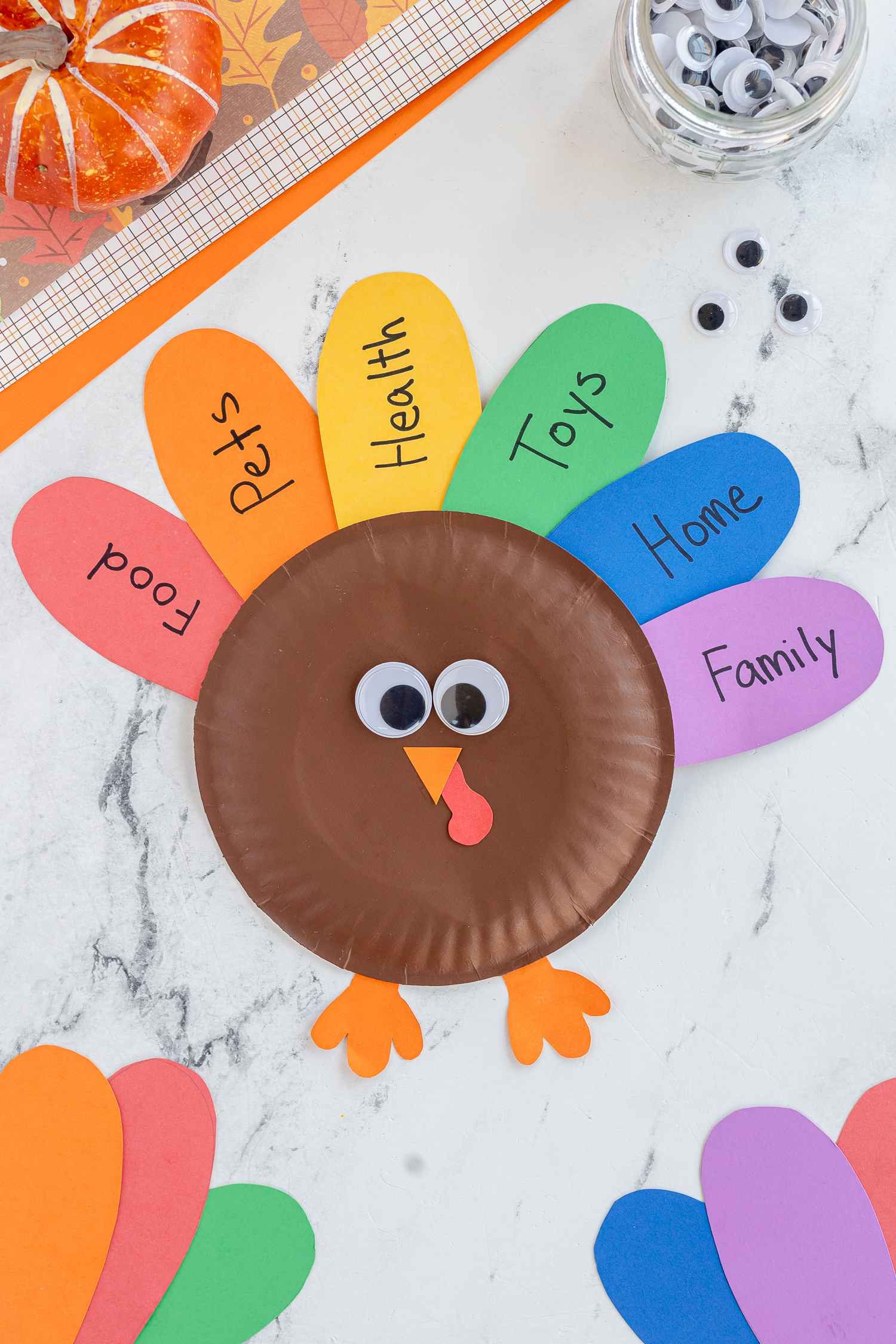 Paper Plate Turkey Craft with colorful feathers and gratitudes written on them