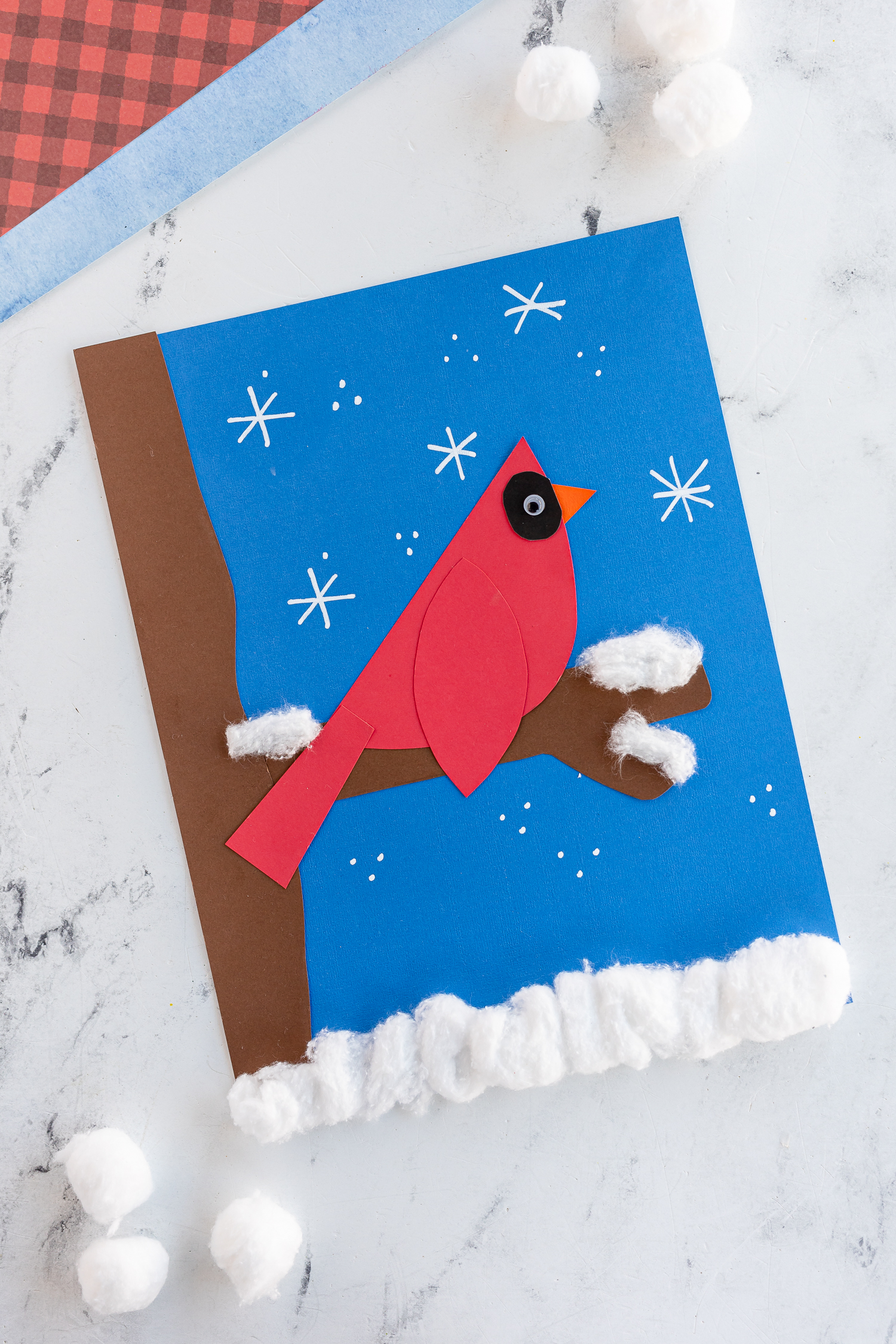 winter cardinal bird made out of paper on blue background