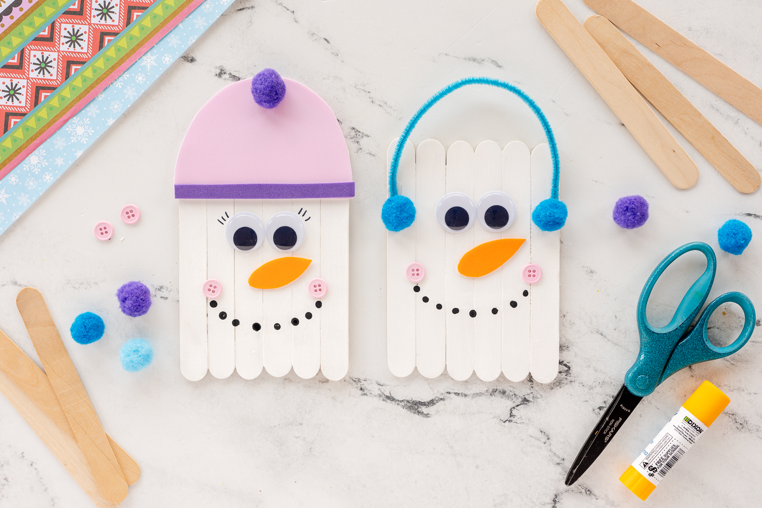 snowmen made from popsicle sticks on table with craft supplies
