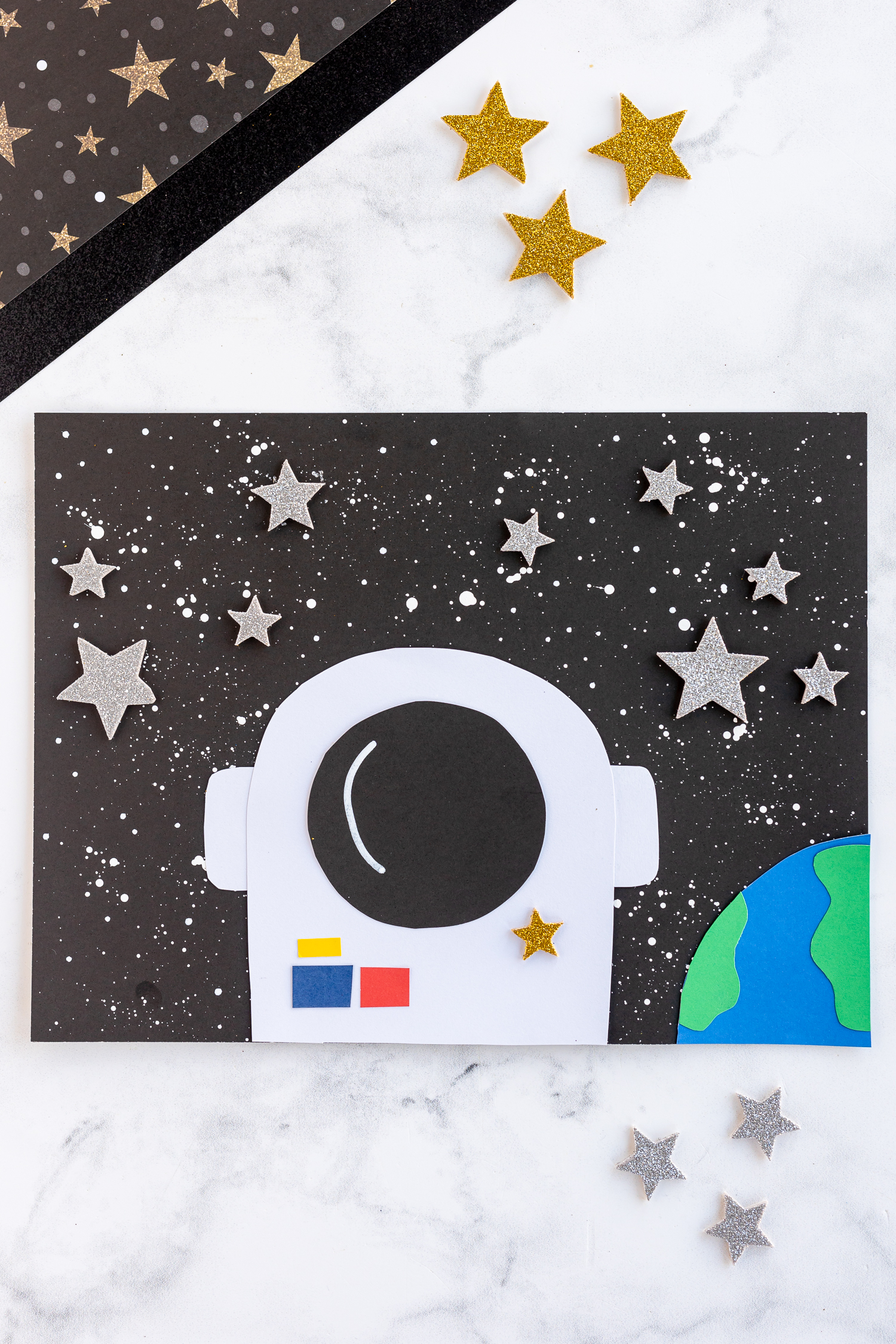 astronaut paper craft on counter with glitter stars
