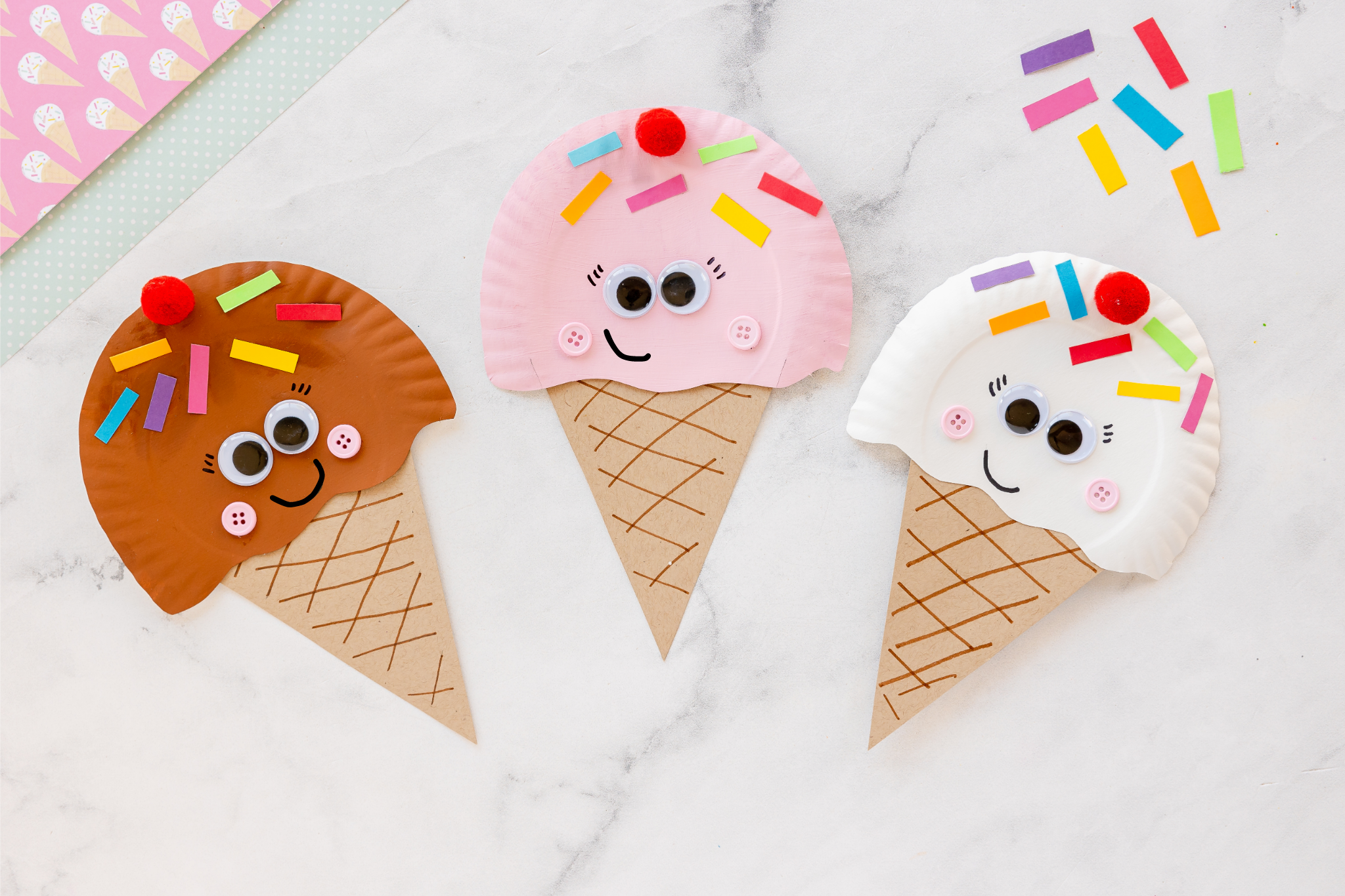 painted paper plate ice cream cone craft on counter with extra cardstock sprinkles