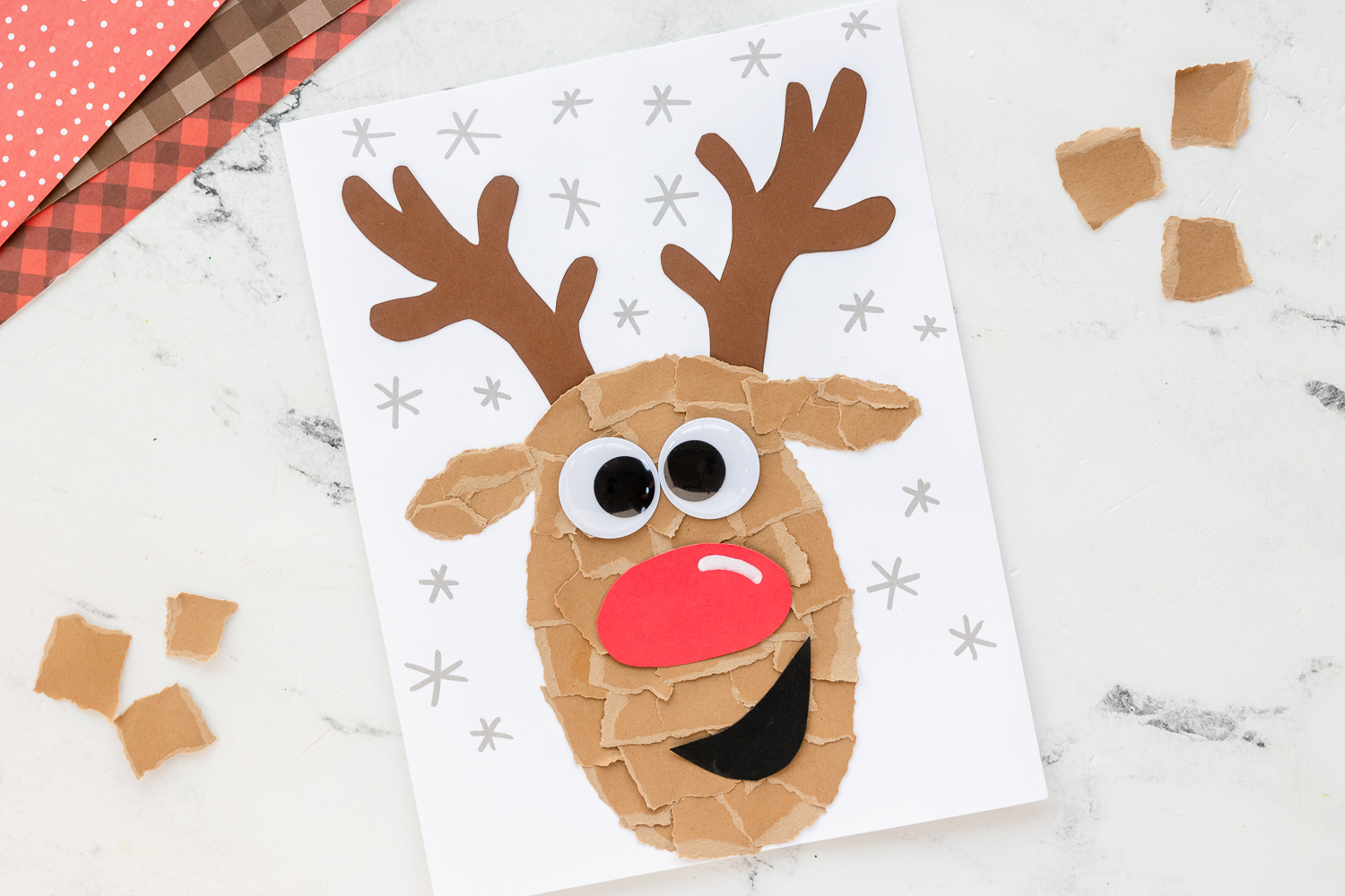 torn paper reindeer craft on counter with torn brown paper beside
