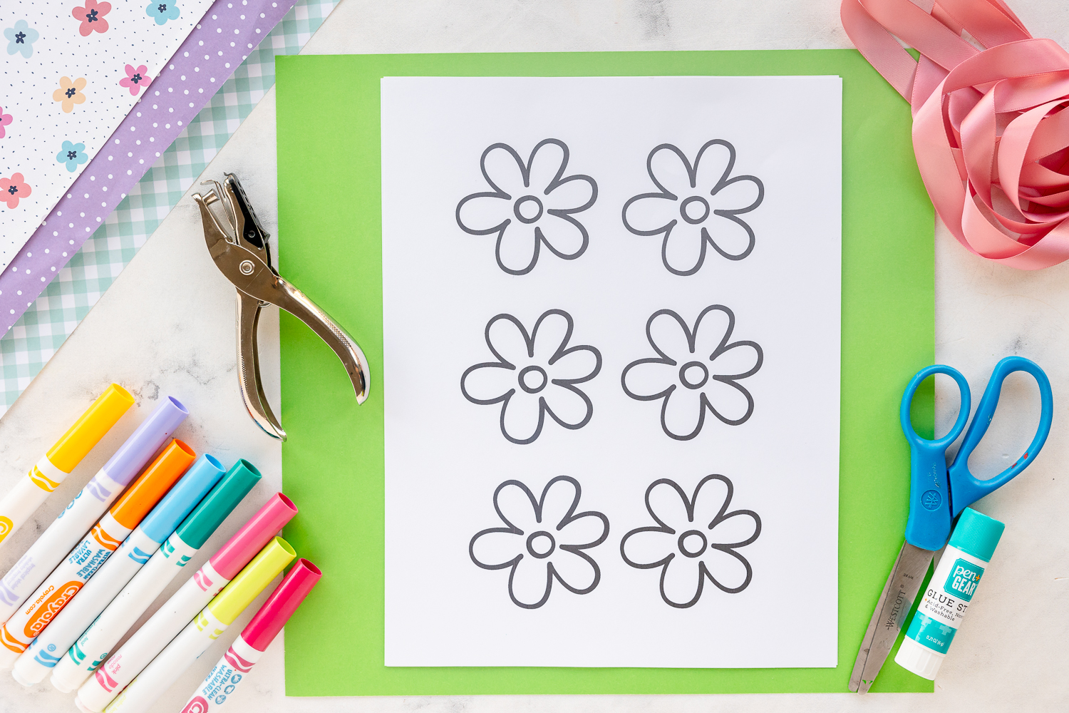 uncolored free printable flower template on counter with markers, scissors and hole punch