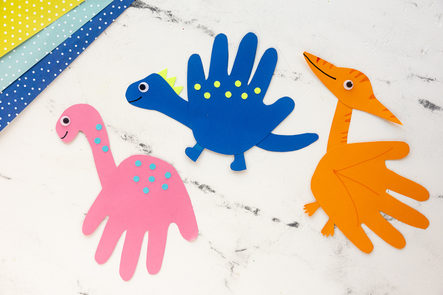 three handprint dinosaurs made from colorful cardstock