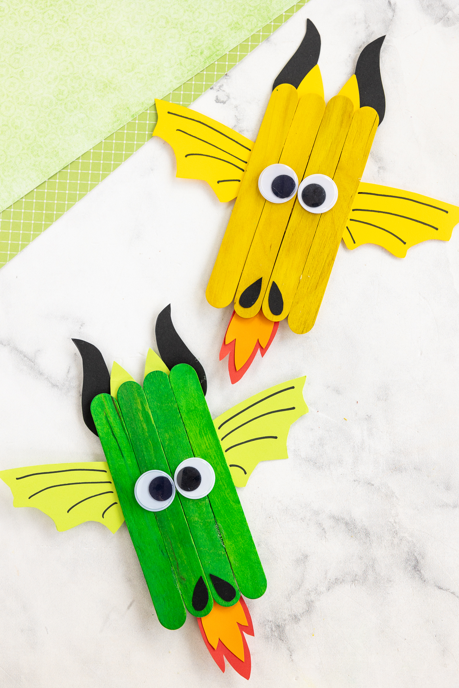 finished dragon craft on craft counter - green popsicle stick and yellow popsicle sticks with paper features