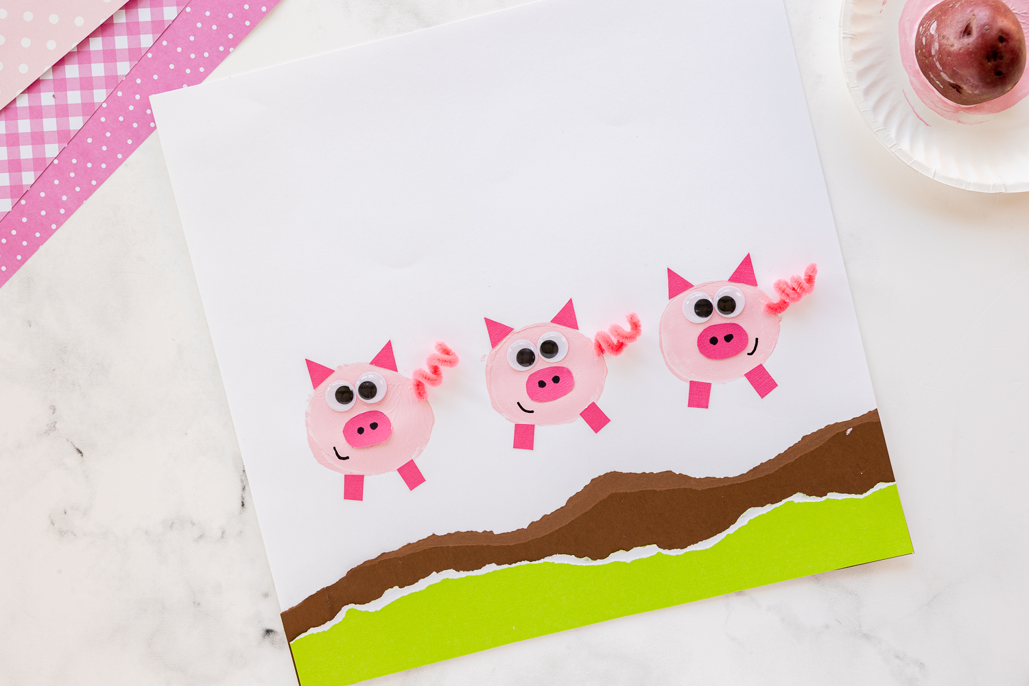 potato stamped pig art with paper plate and potato nearby