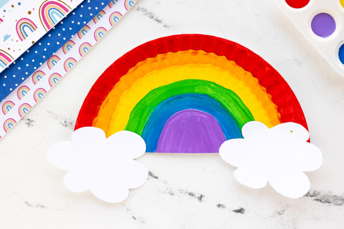 rainbow painted paper plate with white paper clouds on either end