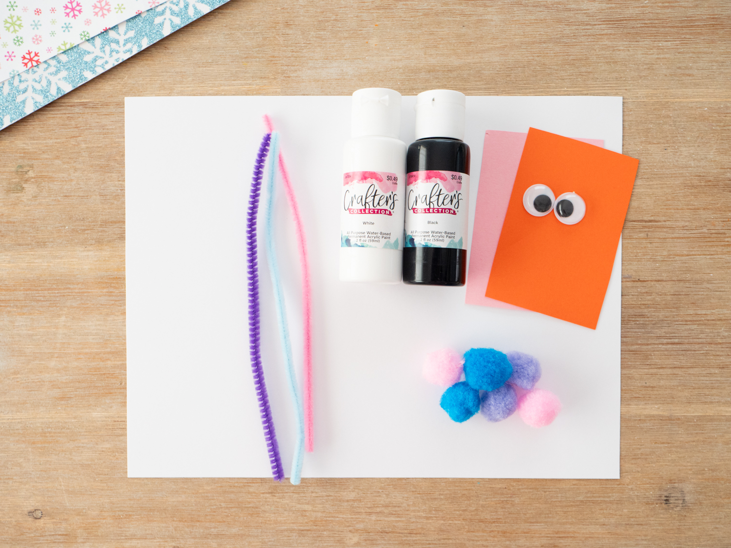 Black and white paint, cardstock, googly eyes, and orange paper for paint scraping penguin craft for kids