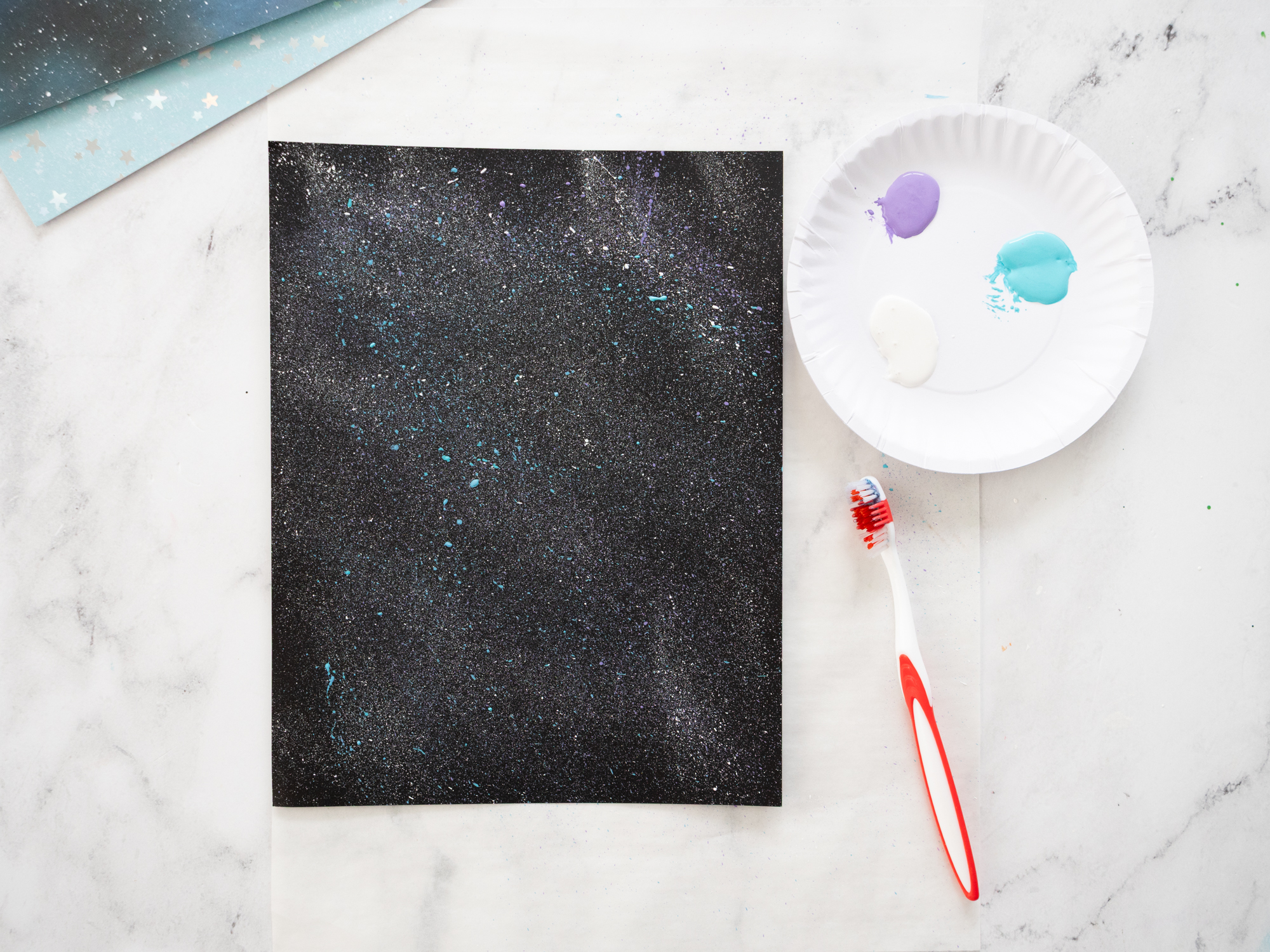 splattering white paint to create outer space stars