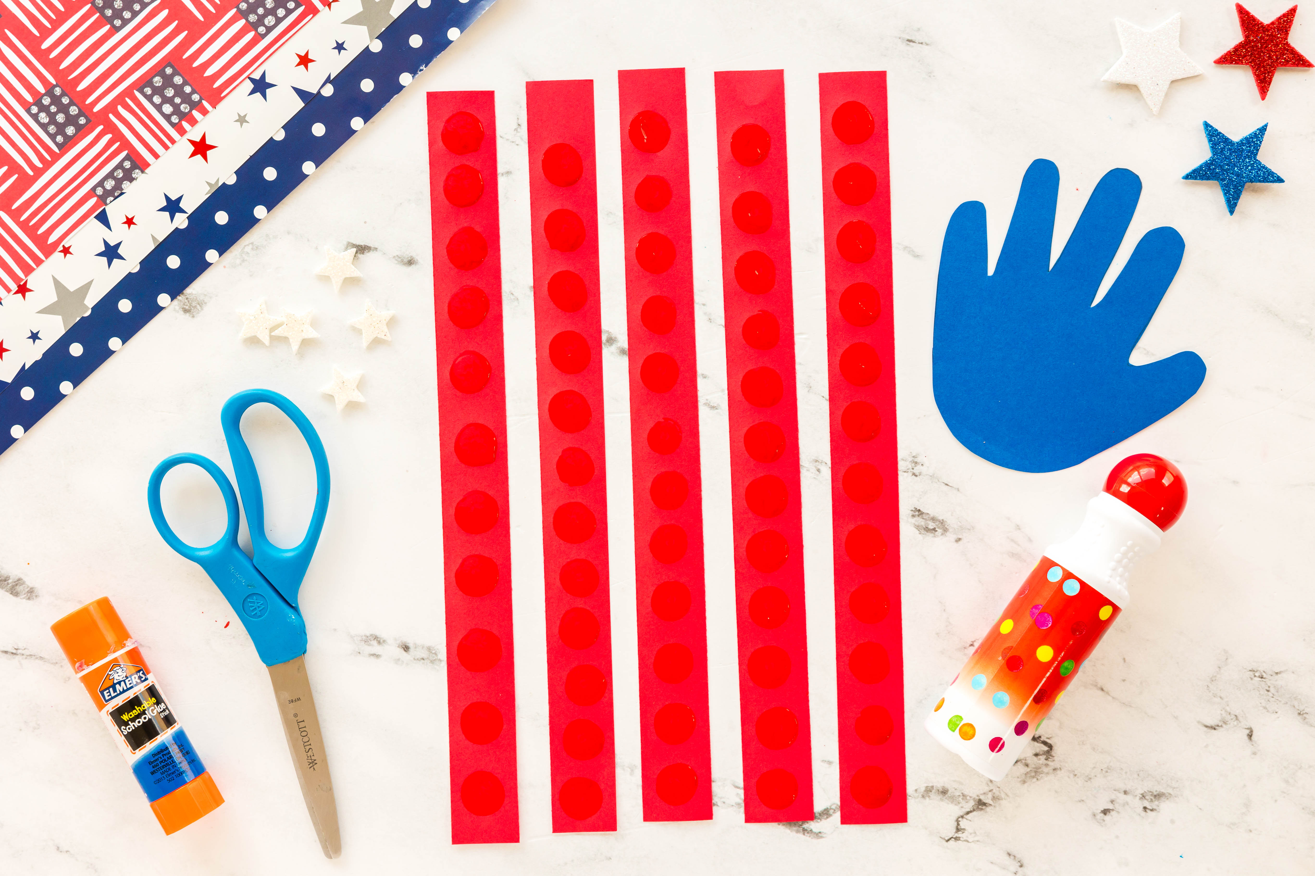 strips of red paper with do a dot stamped on top for handprint flag