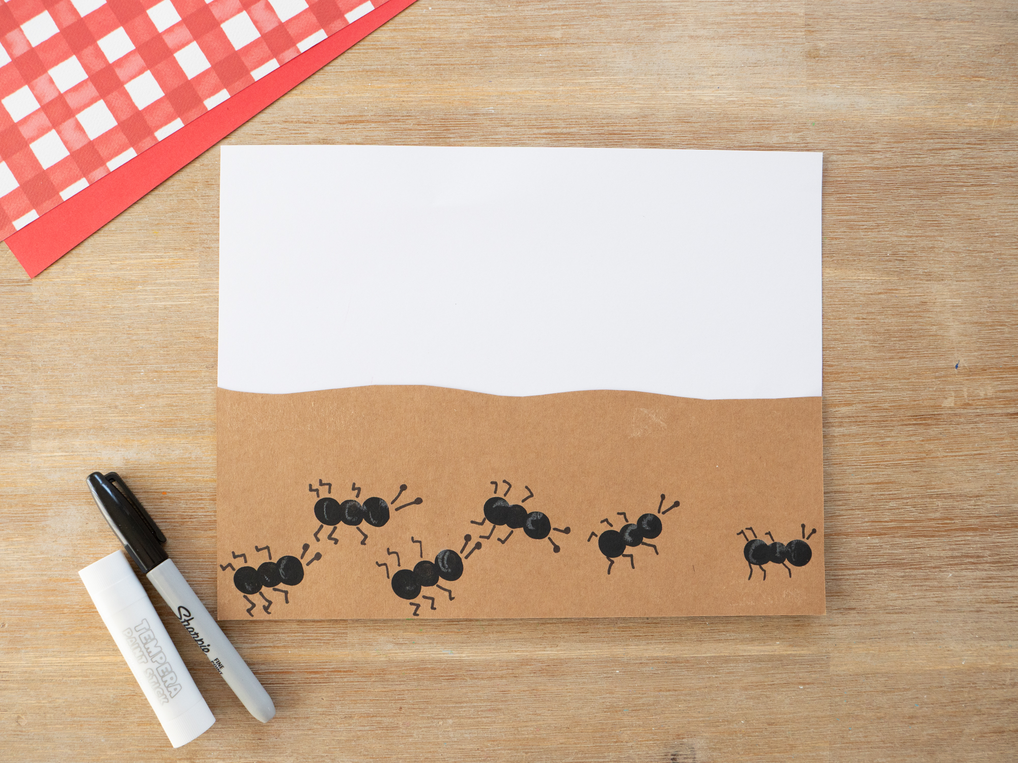 Fingerprint ants stamped with black paint onto brown paper for an ant craft
