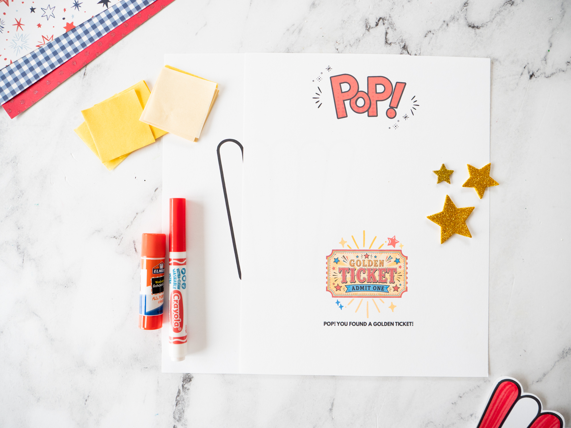 Supplies needed to make a carnival popcorn craft including tissue paper, printable template, glue, scissors, and markers.