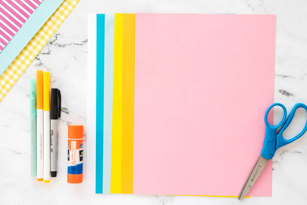 Supplies needed to make a torn paper lemonade craft including colored paper, glue, scissors, cardstock, and printable template