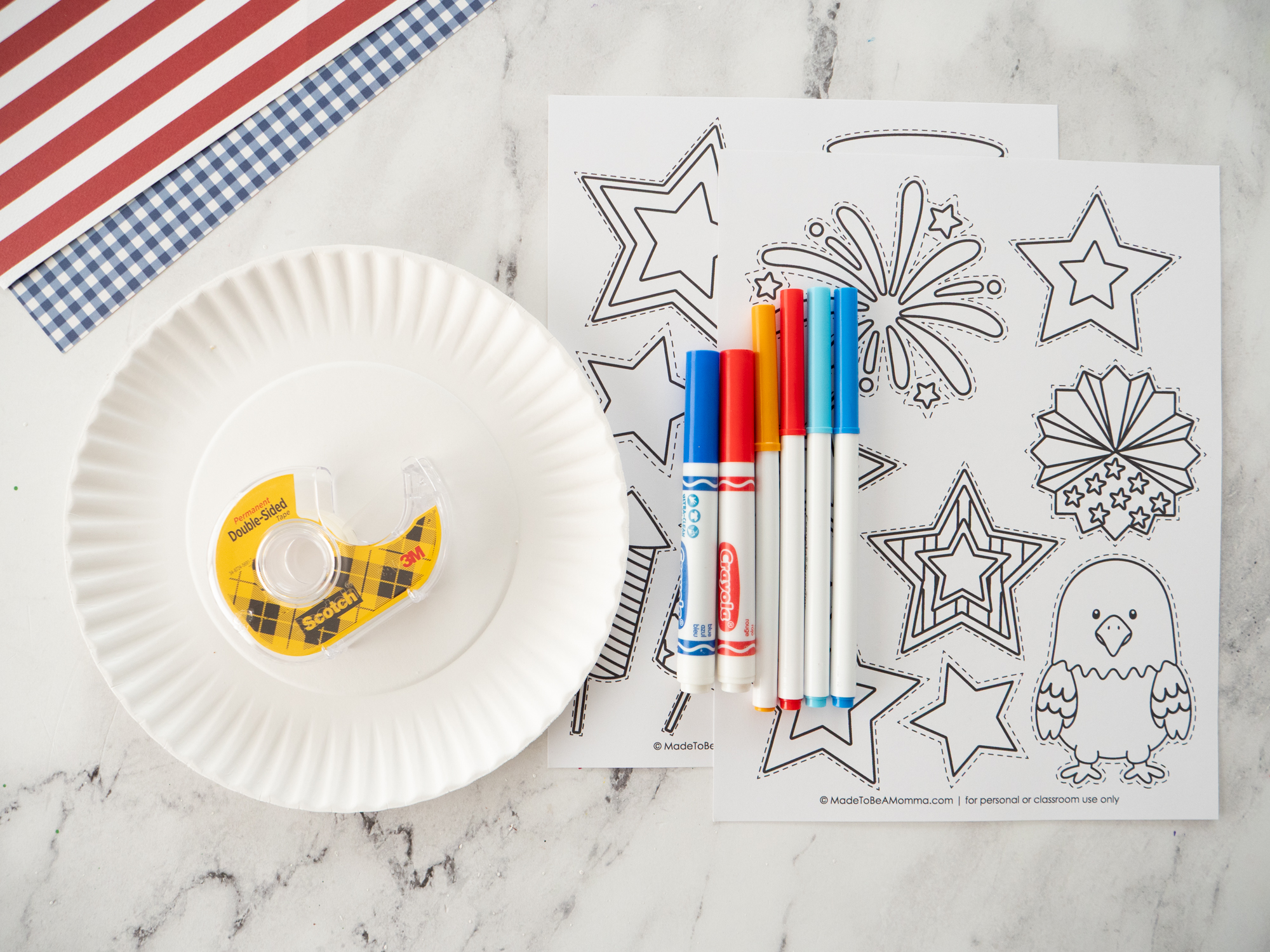 Supplies needed to make a printable Fourth of July wreath craft including paper plate, markers, scissors, glue, and printable template